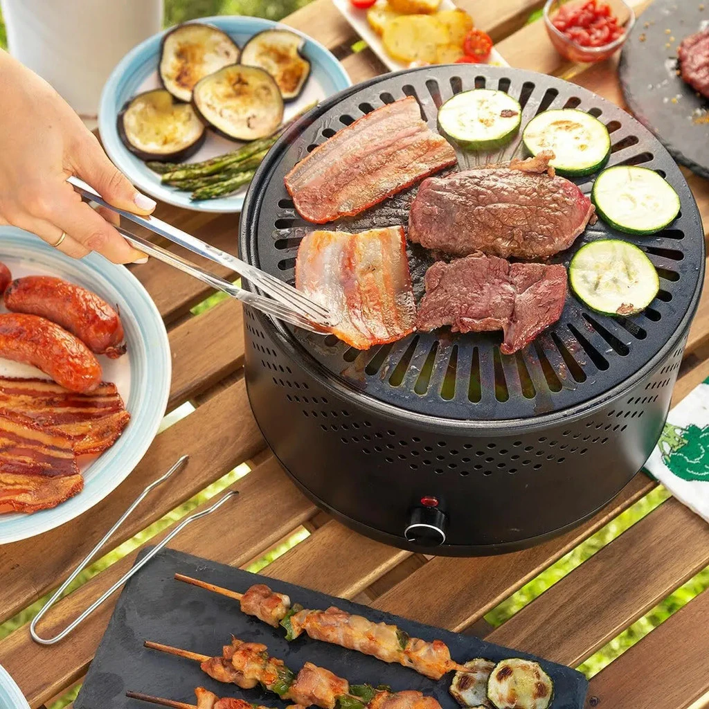 Churrasqueira portátil grelhando carnes e legumes na mesa