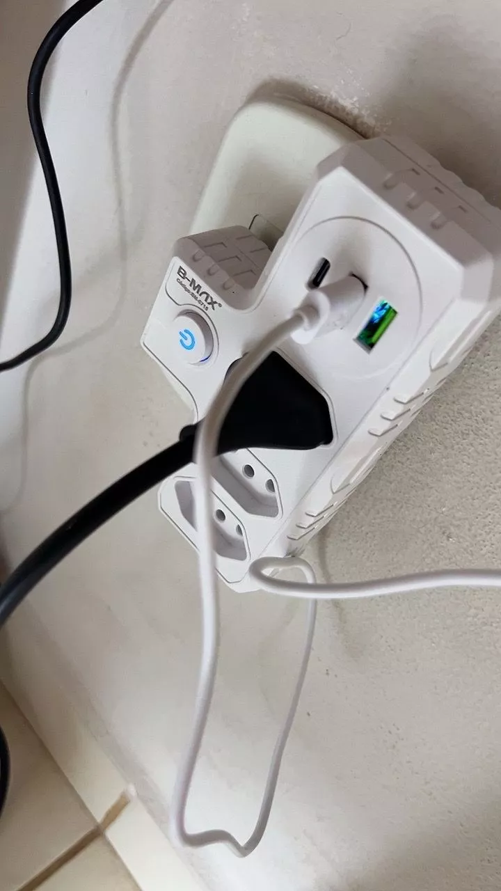 Adaptador instalado na tomada carregando celular